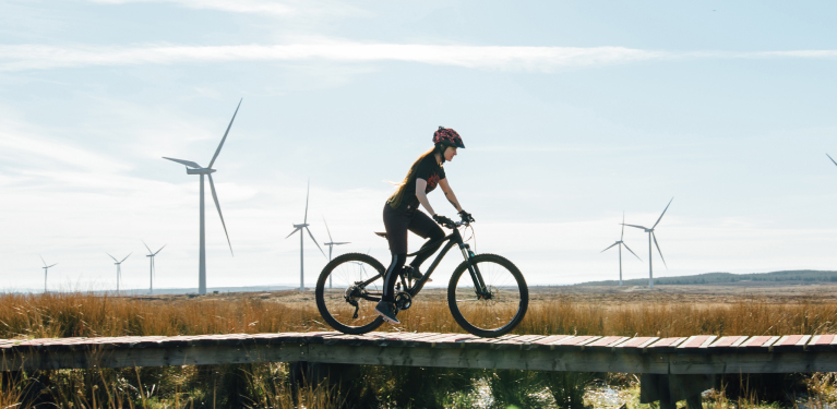 Photo a person on a bike, in a field with wind turbines