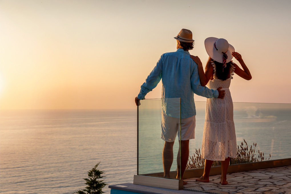 A couple standing on a balcony, gazing at the ocean view.