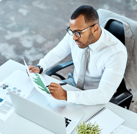 Photo of a man sitting at his desk while holding a paper and pen