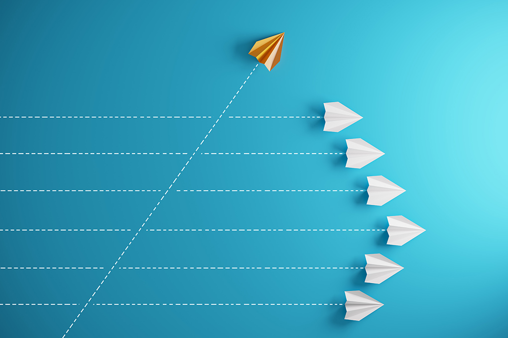 Illustration of 6 white paper planes flying straight ahead and one yellow paper plane flying up